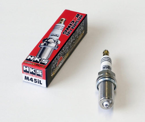 A pack of HKS SUPER FIRE RACING M45iL spark plugs with one plug displayed in front of the packaging.
