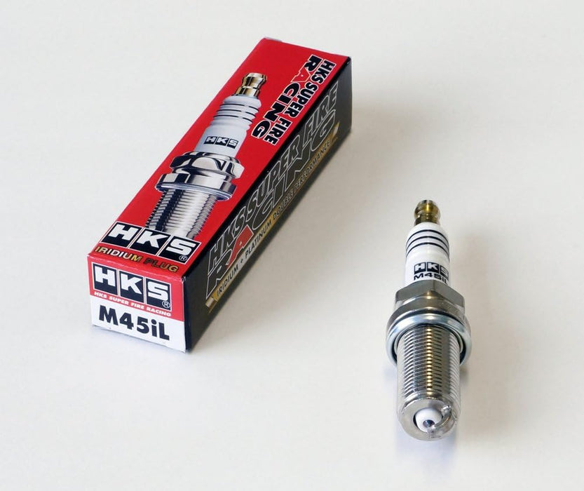 A pack of HKS SUPER FIRE RACING M45iL spark plugs with one plug displayed in front of the packaging.
